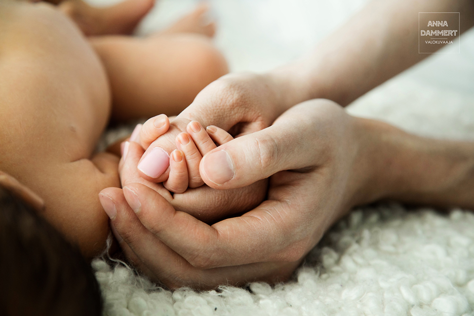 Vanhemmat-pitävät-pientä-vauvaa-kädestä-kiinni-yksityiskohta
